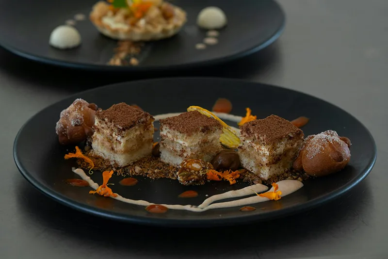 Assiette de dessert avec du tiramisu dressé élégamment du restaurant La Table de Trois à Bordeaux