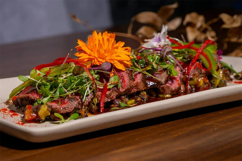 Plat de viande de boeuf gastronomique orné de fleurs comestibles du restaurant La Table de Trois à Bordeaux