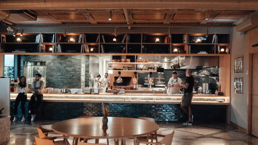 Vue de la salle de restaurant avec cuisine ouverte et l’équipe présente de La Table de Trois à Bordeaux. Contacter l'Équipe du Restaurant pour la rejoindre.